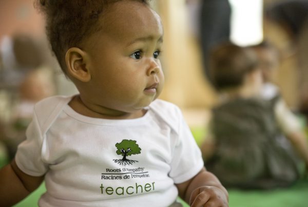 a baby in a Roots of Empathy t shirt